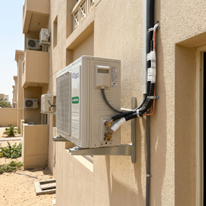 Outdoor AC unit installation with secure mounting brackets and insulated copper piping in a realistic UAE exterior setting