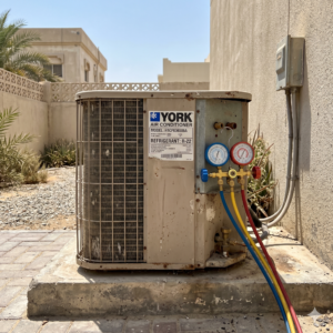Outdoor R22 AC condenser unit with gauges attached, clean setup in a realistic UAE environment, no people, square frame